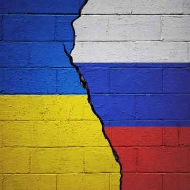 Cracked brick wall painted with a Ukrainian flag on the left and a Russian flag on the right