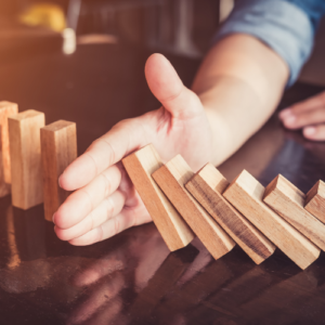 Business man stopping dominos from falling