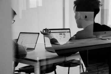 people in meeting room in front of laptops