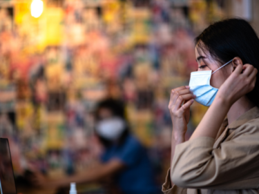 A Chinese lady pulling up her mask to protect herself from COVID