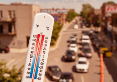 Thermometer in front of cars and traffic during heatwave in Montreal