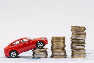 toy-car-going-up-increasing-stack-coins-against-white-background
