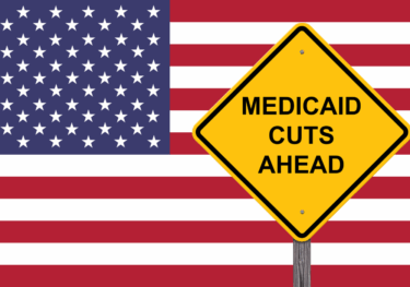 Photo of a sign saying Medicaid cuts ahead of an American flag